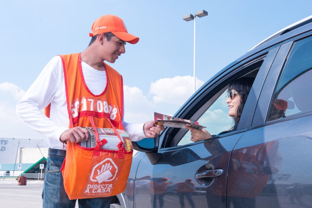 Promotor de Directa a Casa entregando publicidad a una conductora